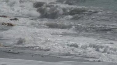 Dalgalar kıyıya beyaz köpükle vuruyor.