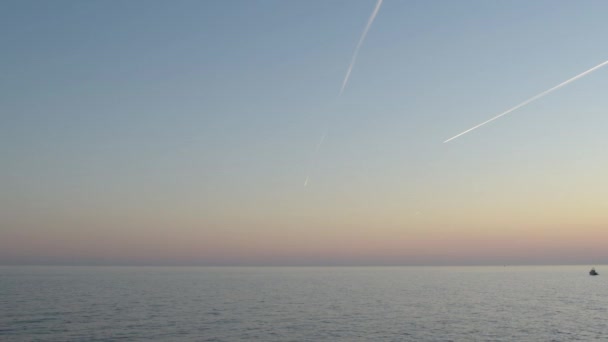 夕阳西下的海面上 有渔船 空中有喷射反应堆的烟道 — 图库视频影像