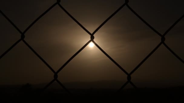 雲の間の日没時に太陽とワイヤーフェンス — ストック動画