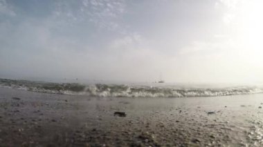 Sahildeki dalgalar kameraya yansıyor. Yavaş çekim