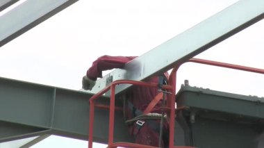 Bir endüstriyel depodaki metal yapının montajında görevli.