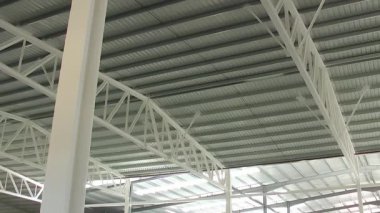 Elektrikli makas asansöründeki işçiler endüstriyel bir deponun tepesinde çalışıyorlar.