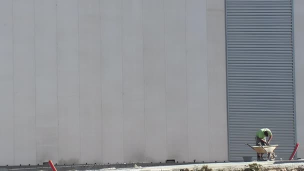 工業倉庫の大きなファサードの隣にハンドガード付きのブリックレイヤー — ストック動画