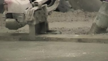 Tuğla ustası, güçlü titreşimli makineyle taze betonu düzleştiriyor.