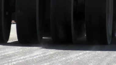 Bir yoldaki katranı görüntüleyen sıkıştırıcı veya buharlı silindir tekerlekleri