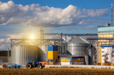Ukrayna. Kyiv. 20 Ağustos 2022. Yeni Hollanda traktörü bir tarım silosunun yanında çalışıyor.