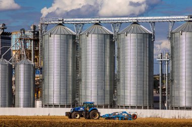 Ukrayna. Kyiv. 20 Ağustos 2022. Yeni Hollanda traktörü bir tarım silosunun yanında çalışıyor.