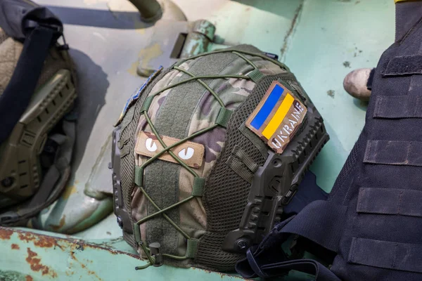 一个戴着防弹背心坐在装甲车上的乌克兰士兵的军事头盔 乌克兰国旗作为象征 免版税图库照片
