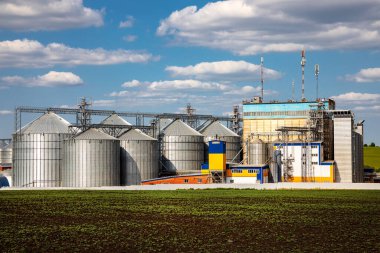 Tarım Siloları. Tahıl depolama ve kurutma tahıl, buğday, mısır, soya, ayçiçeği beyaz bulutlu mavi gökyüzüne karşı. Ekin depolama.