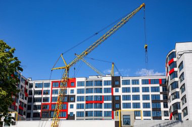 Yeni bir apartman bloğu üzerinde çalışıyoruz. Vinçlerle birlikte inşaat halindeki yüksek bina. Yeni Bina İnşaat Alanı.