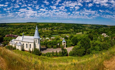 Catholic church in the Ukrainian village of Zinkiv. Rural landscape with a beautiful church on a summer day.