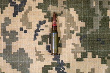 Ukrayna ordusunun piksel kamuflaj üniformasının arka planında bulunan makineli tüfekten çıkan bir fişek. Ukrayna 'da Savaş.