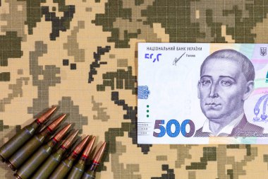 Ukrayna ordusunun piksel kamuflaj üniformalarının arka planında bir makineli tüfek ve Ukrayna Hryvnia fişeği. Ukrayna 'da Savaş.