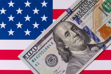 Amerika Birleşik Devletleri bayrağının arka planına karşı 100 Amerikan doları.
