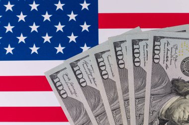 Amerika Birleşik Devletleri bayrağının arka planına karşı 100 Amerikan doları.