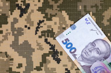 Ukrayna ordusunun piksel kamuflaj üniformalarının arka planında Ukrayna hryvnia 'sı. Ukrayna 'da Savaş.