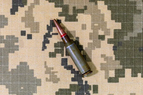 Ukrayna ordusunun piksel kamuflaj üniformasının arka planında bulunan makineli tüfekten çıkan bir fişek. Ukrayna 'da Savaş.