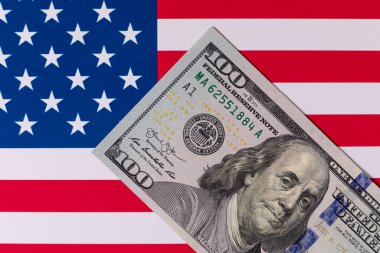 Amerika Birleşik Devletleri bayrağının arka planına karşı 100 Amerikan doları.