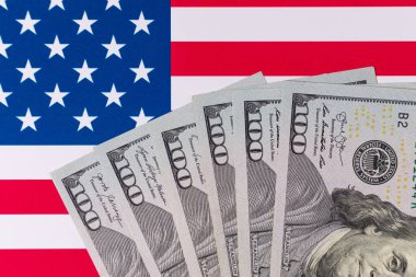 Amerika Birleşik Devletleri bayrağının arka planına karşı 100 Amerikan doları.