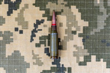 Ukrayna ordusunun piksel kamuflaj üniformasının arka planında bulunan makineli tüfekten çıkan bir fişek. Ukrayna 'da Savaş.
