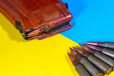 Bir makineli tüfek fişeği ve Ukrayna bayrağının arkasında bir şarjör. Ukrayna 'da Savaş.