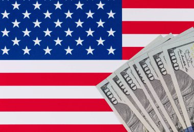 Amerika Birleşik Devletleri bayrağının arka planına karşı 100 Amerikan doları.