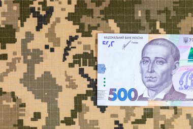Ukrayna ordusunun piksel kamuflaj üniformalarının arka planında Ukrayna hryvnia 'sı. Ukrayna 'da Savaş.