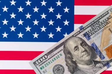 Amerika Birleşik Devletleri bayrağının arka planına karşı 100 Amerikan doları.