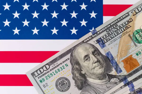 Amerika Birleşik Devletleri bayrağının arka planına karşı 100 Amerikan doları.