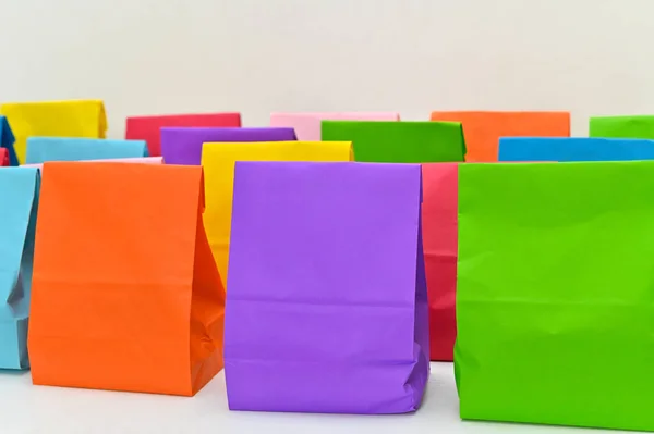 Beyaz arka planda izole edilmiş renkli katlanmış kağıt poşetler. Kağıt alışveriş poşetleri, boş dikdörtgen hediye paketleri. Markalaşma ve kurumsal kimlik tasarımı için hazırlan.
