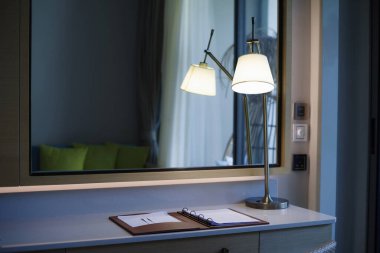 Odadaki masada bir lamba vardı. Arkada bir ayna var..