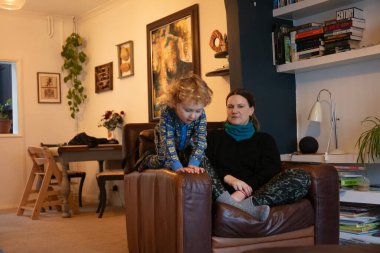 Kafkasyalı pijamalı çocuk, annesiyle koltukta oynuyor..