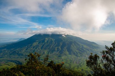 Merbabu Dağı Ulusal Parkı 'nın panoramik manzarası. Tepesinde bulutlardan oluşan bir daire.