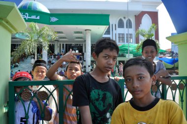 Pamekasan, Jawa Timur, Madura island, Indonesia - June 4, 2010: group of Indonesian children looking at camera with curiosity outside of the Mosque. clipart