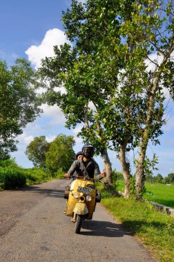 Sumenep, Madura Adası, Doğu Java, Endonezya - Haziran 05, 2010: Endonezyalı bir adam açık havada sarı Vespa motosikleti kullanıyor..