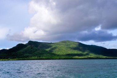 Okyanustan tropikal ada Karimunjawa 'ya kadar panoramik manzara. Bulutlu bir gökyüzünün altındaki tepede turkuaz su ve yemyeşil bitki örtüsüyle. Jepara naipliği, merkez Java, Endonezya