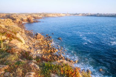 Atlantik Okyanusu 'nun güneşli kayalık kıyıları batan güneş ışınları, Papoa Adası, Peniche, Portekiz