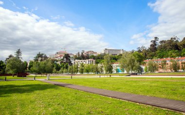 Eski şehrin yeşil bitki örtüsü ve tarihi binaları, bulutlu gökyüzünün arka planına karşı, Coimbra, Portekiz