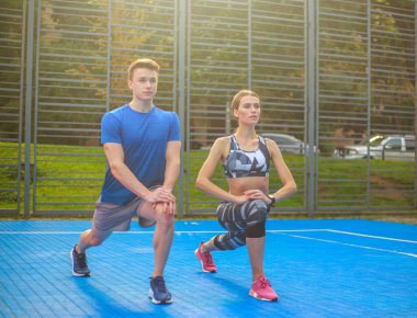 Genç mutlu ve odaklanmış çift spor yapıyor, şehir spor sahasında spor yapıyor.