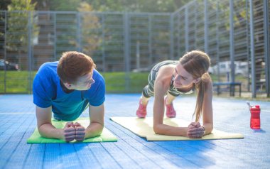 Genç mutlu ve odaklanmış çift spor yapıyor, şehir spor sahasında spor yapıyor.