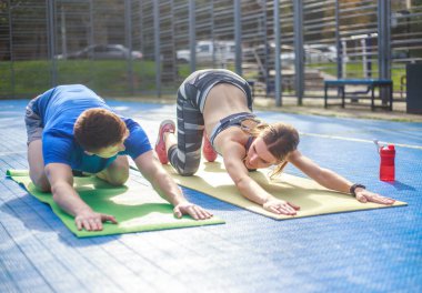 Genç mutlu ve odaklanmış çift spor yapıyor, şehir spor sahasında spor yapıyor.