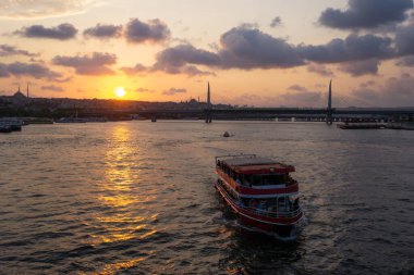 Günbatımında İstanbul kentinin önündeki turist botu