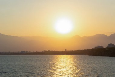 Antalya şehri üzerinde gün batımı ve arka planda dağlar