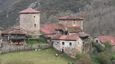 Ortaçağ köyünün taştan yapılmış ve kırmızı kiremitlerle kaplı birkaç binasının görüntüsü.