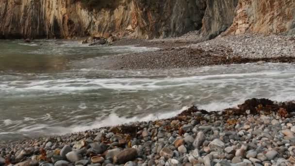 Ocean Waves Crash Rounded Pebbles Gravel Beach Foot Cliffs — Stock Video