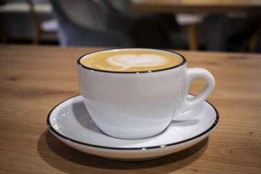 Masada bir fincan cappuccino. Kahve. Sıcak kahve içeceği. Beyaz fincan ve çay tabağı..
