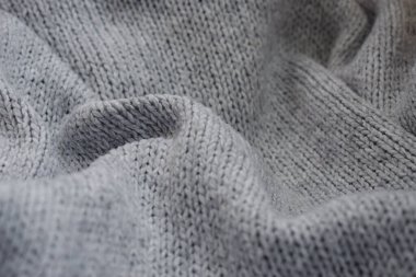 Gri örülmüş yün dokusu arka planı kapatır. Dalgalı kumaşı katlar. Ev atmosferinde konforlu kompozisyon.