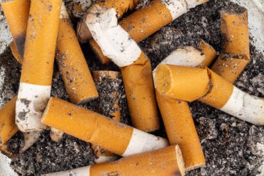Close-up of cigarette butt and ashes on a plain background.