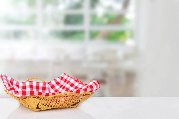 Empty picnic basket. Close-up of a empty straw basket with a checkered red napkin on table over blurred kitchen background. For your food and product display montage.