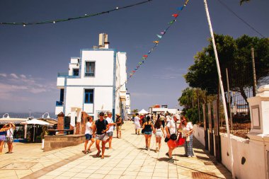 Puerto de las Nieves, island of Gran Canaria Spain  20 Jul 2024. Tourists and locals on the streets with typical white-blue romantic architecture port town. clipart